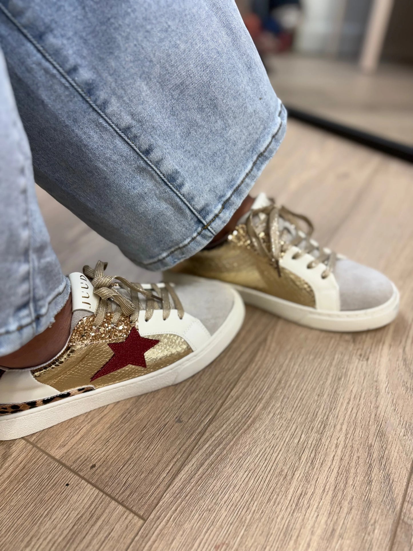 Gold and white sneakers with a red star on a wooden floor