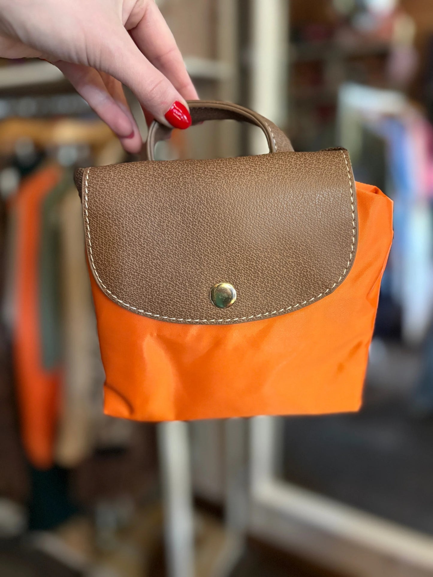 Hand holding a brown and orange bag with blurred background