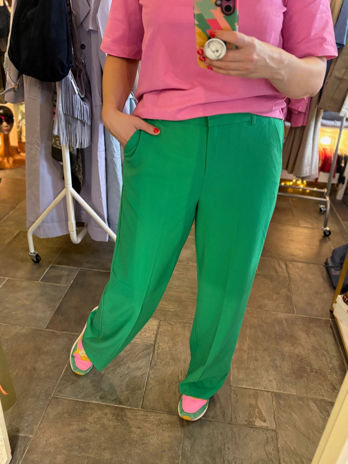 Person wearing a pink shirt and green pants in a store setting