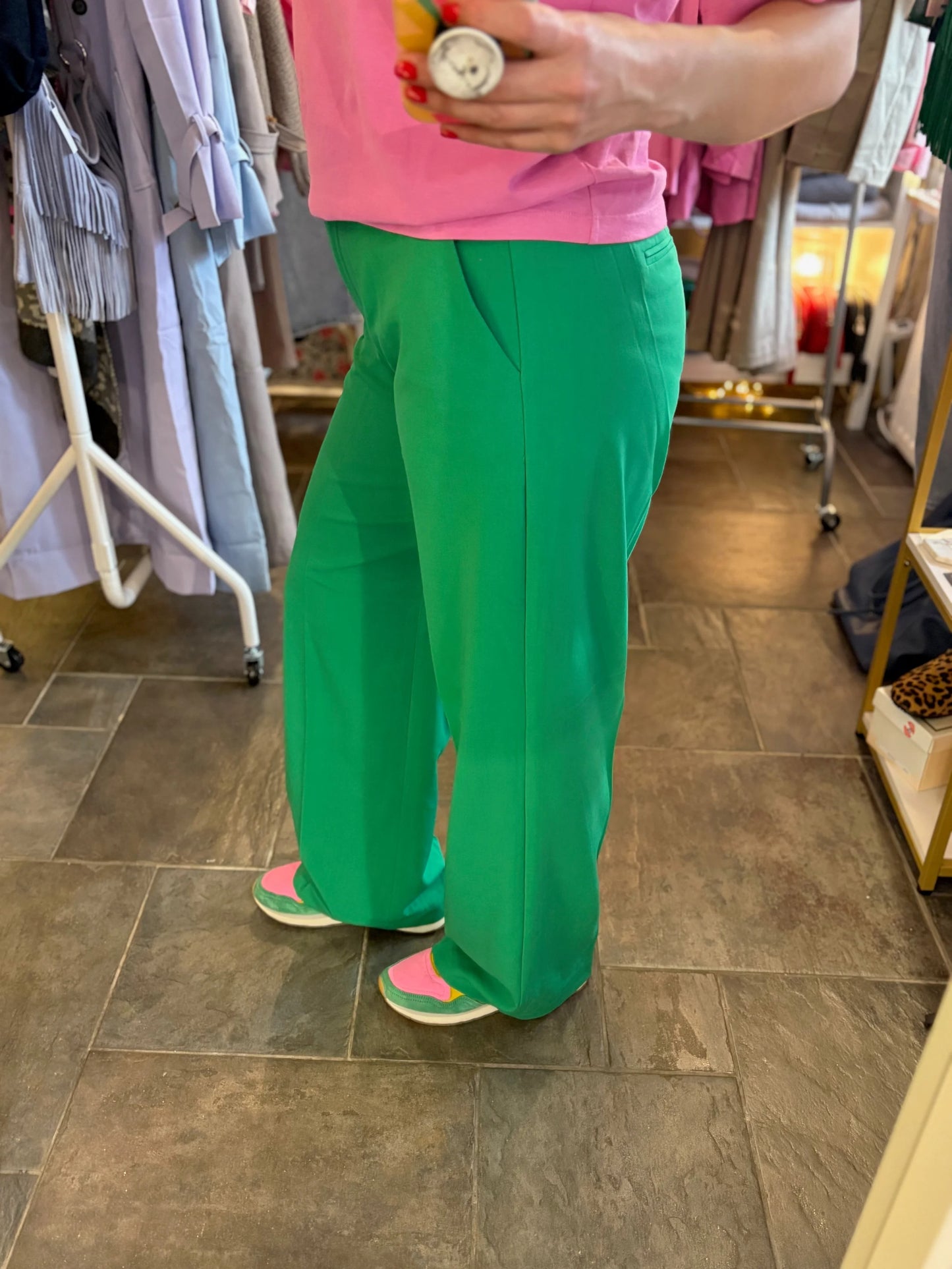 Person wearing green pants and pink shirt in a store setting