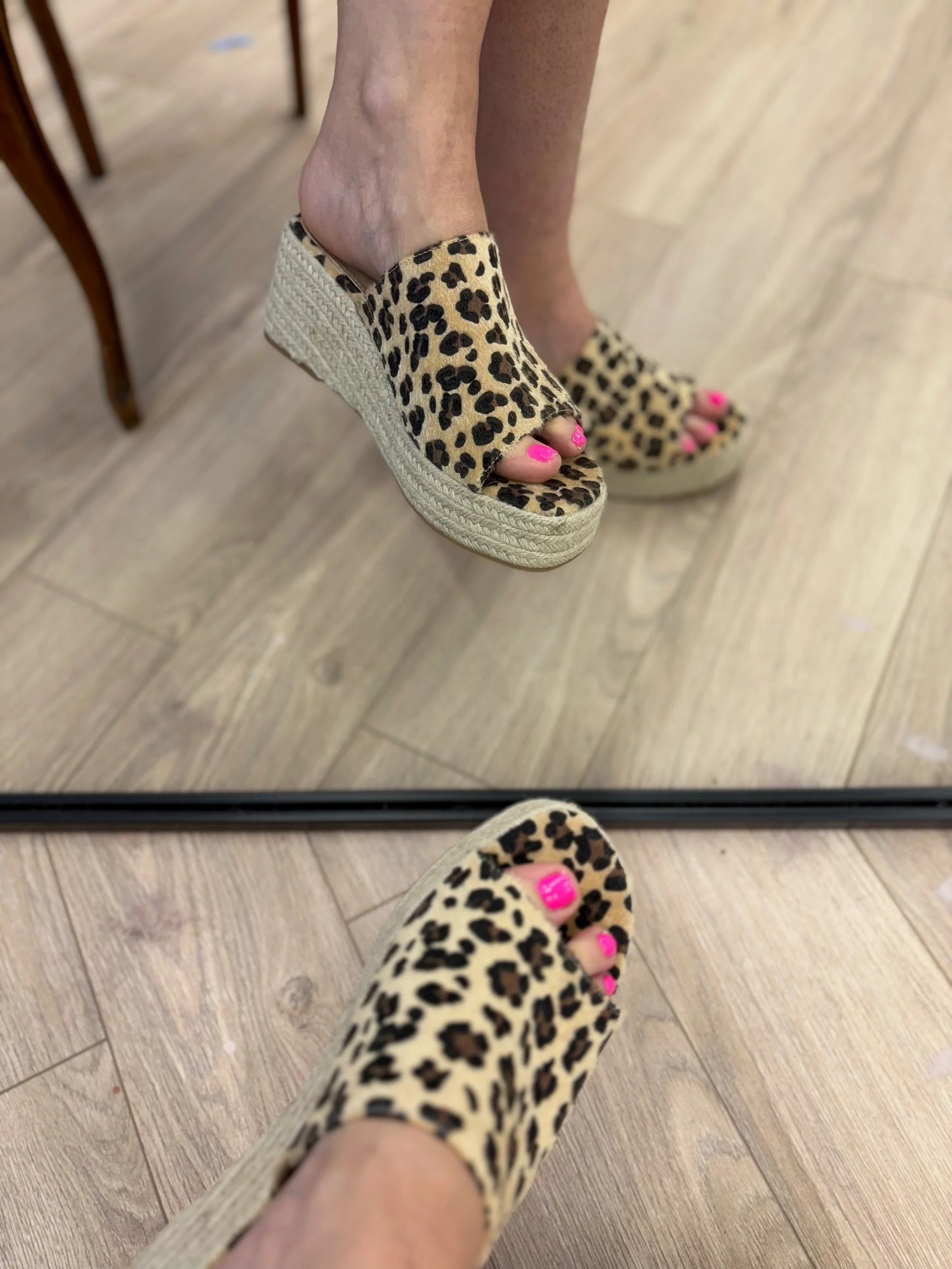 Leopard print sandals worn on a wooden floor