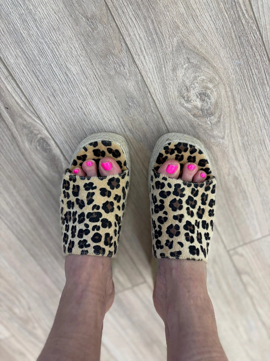 Leopard print slippers worn on a wooden floor