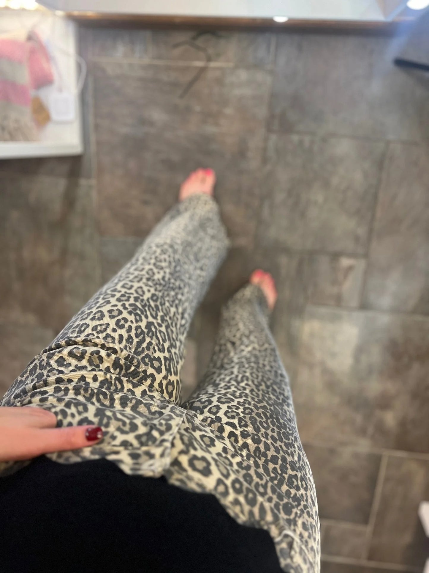 Person wearing leopard print pants standing on a tiled floor.