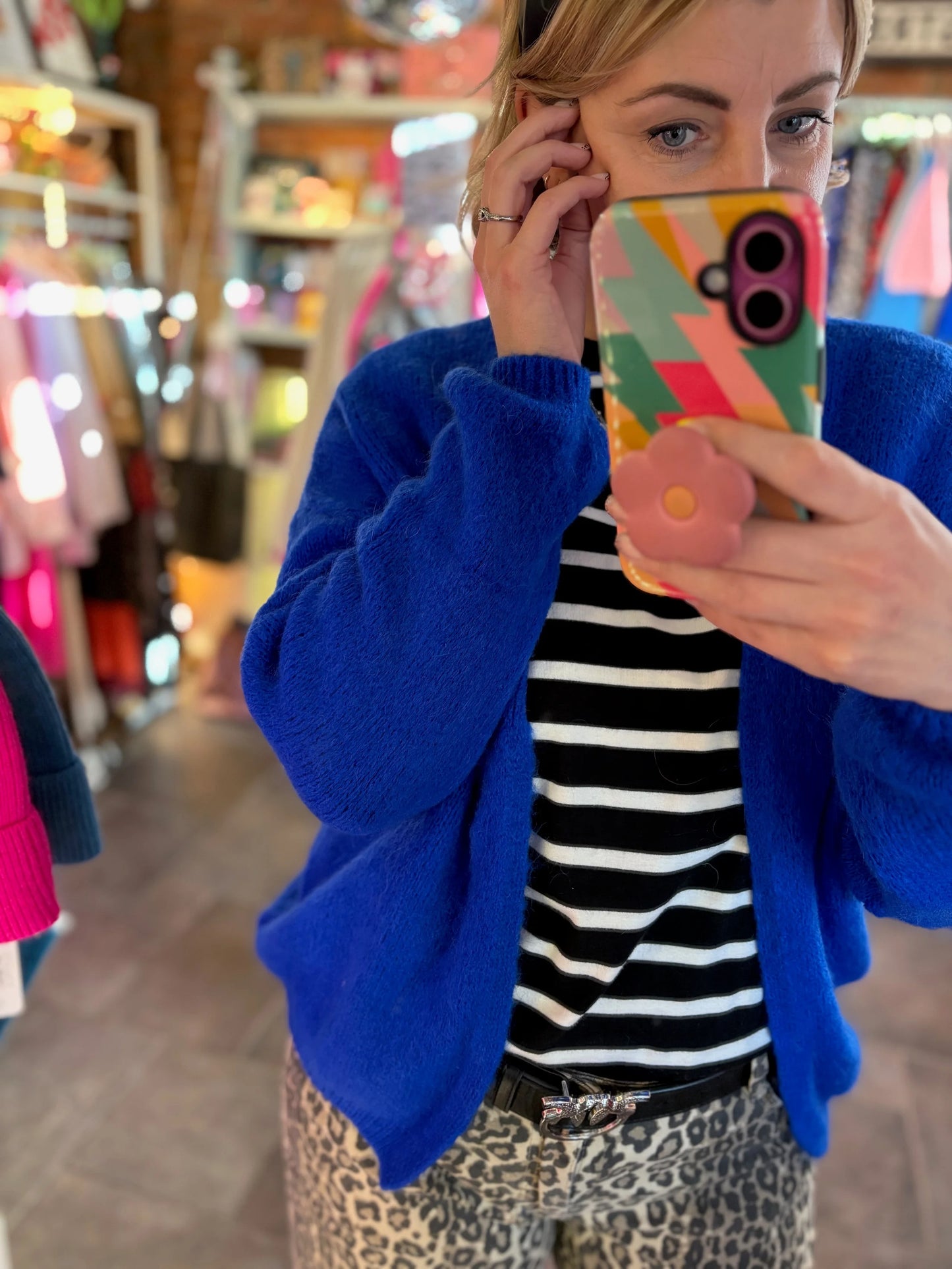 woman taking selfie in shop with blue mohair cardigan and leopard print jeans