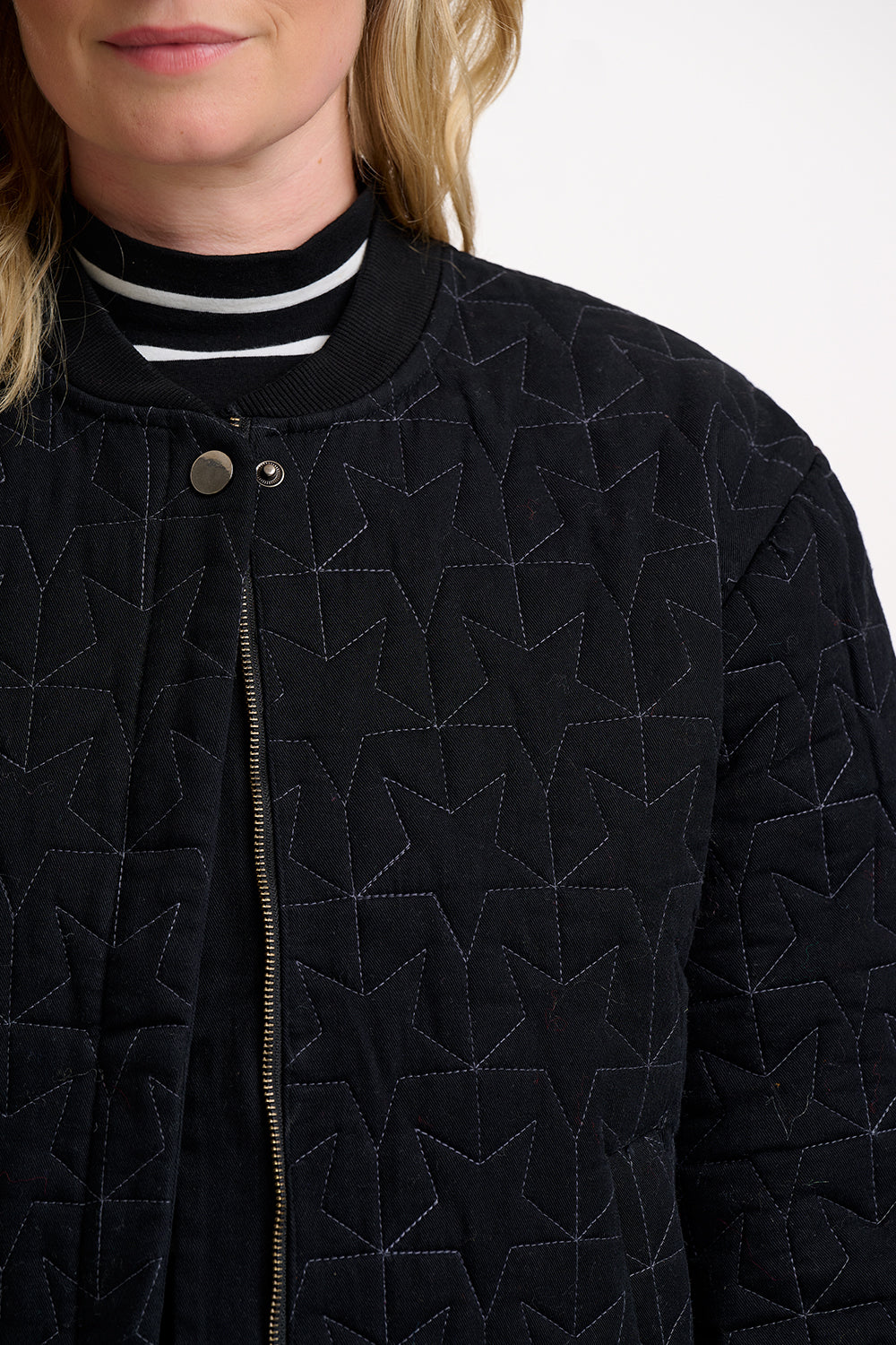 Close-up of a person wearing a black quilted jacket with geometric star pattern