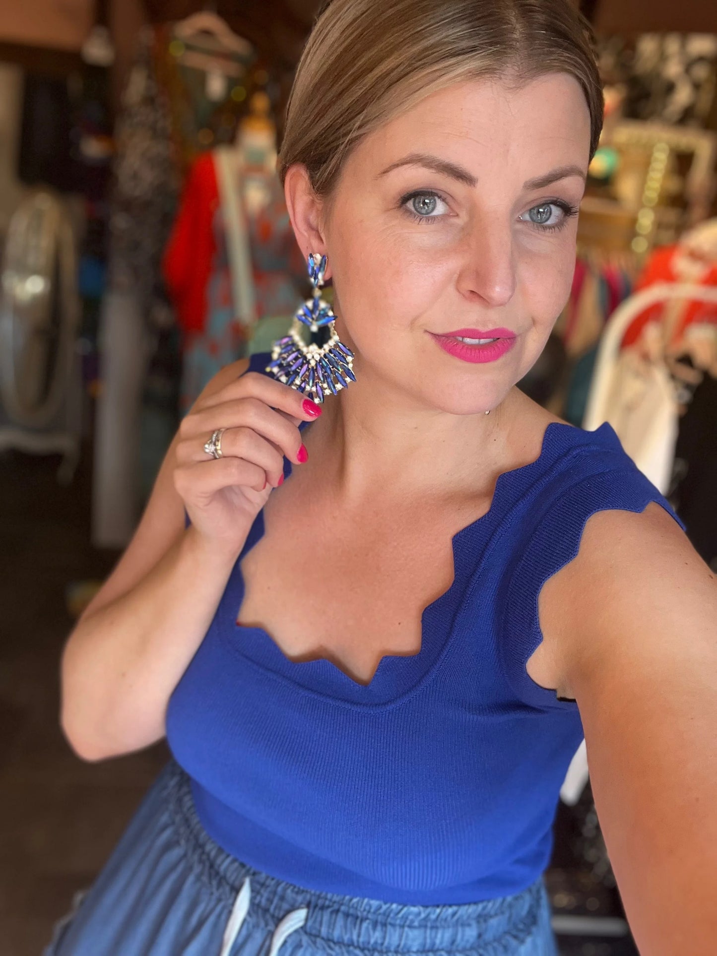 Woman wearing a blue top and large earrings in an indoor setting