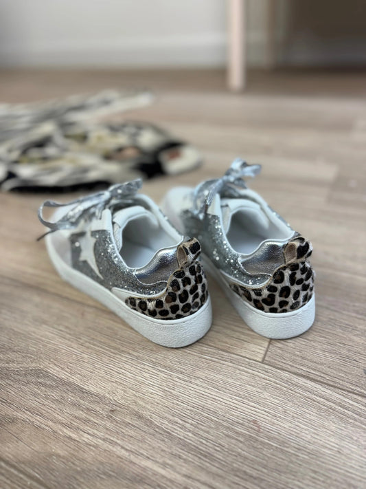Pair of children's sneakers with leopard print details on a wooden floor.