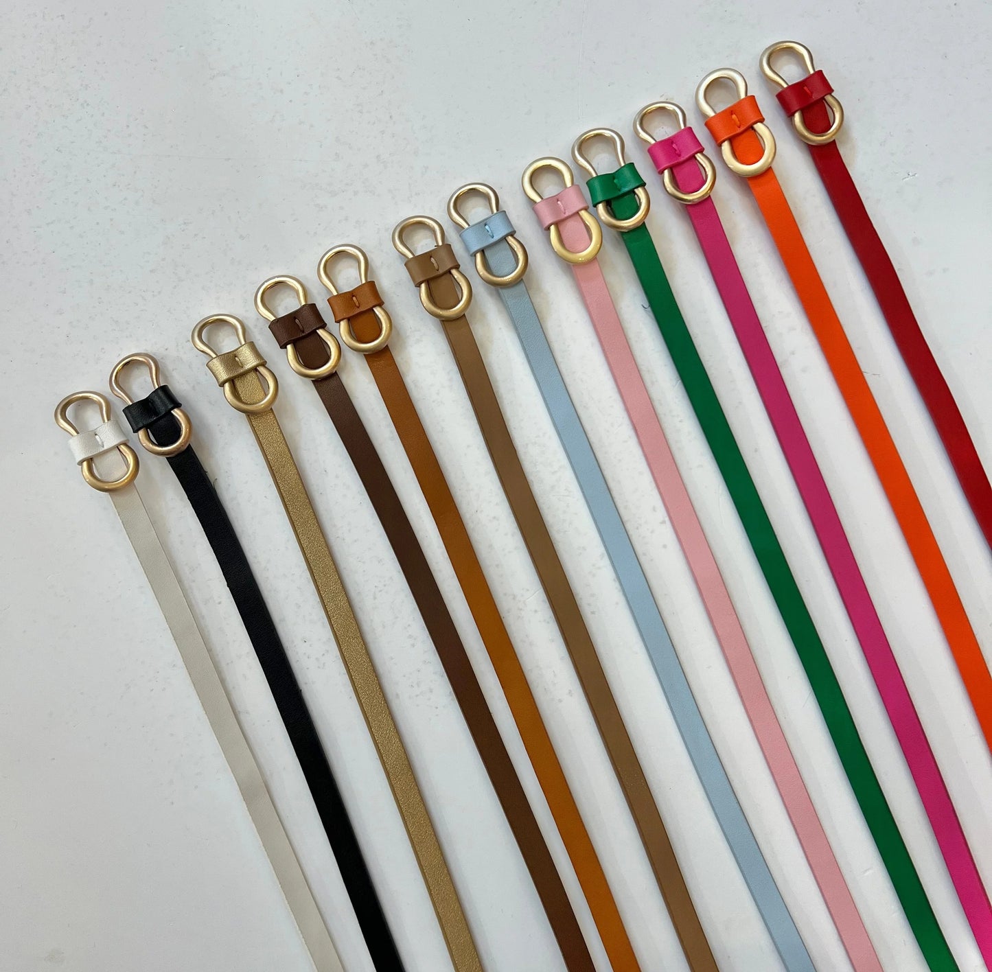 Set of colorful leather straps with gold hooks on a light gray background
