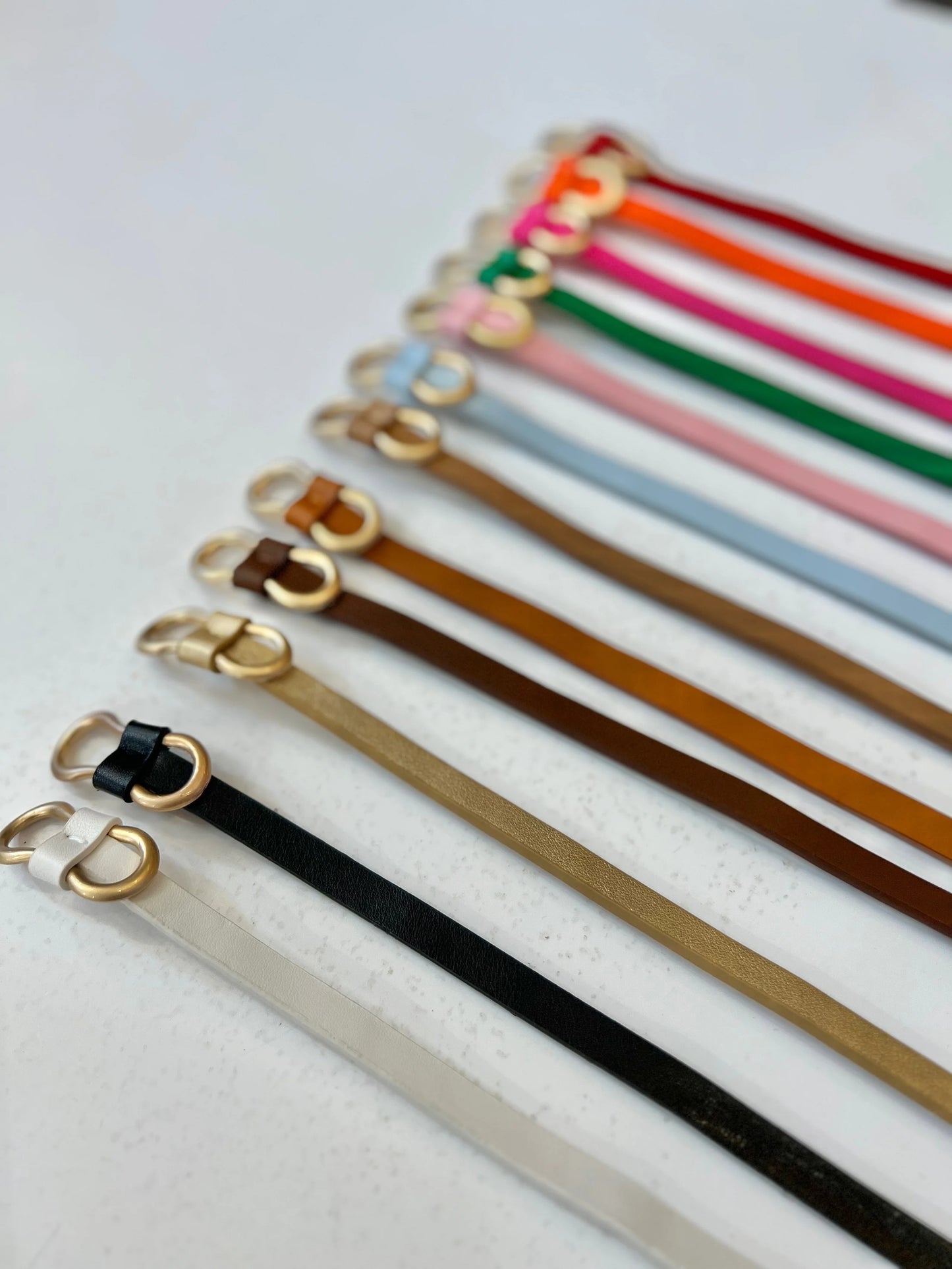 Set of colorful leather straps with gold buckles on a light background