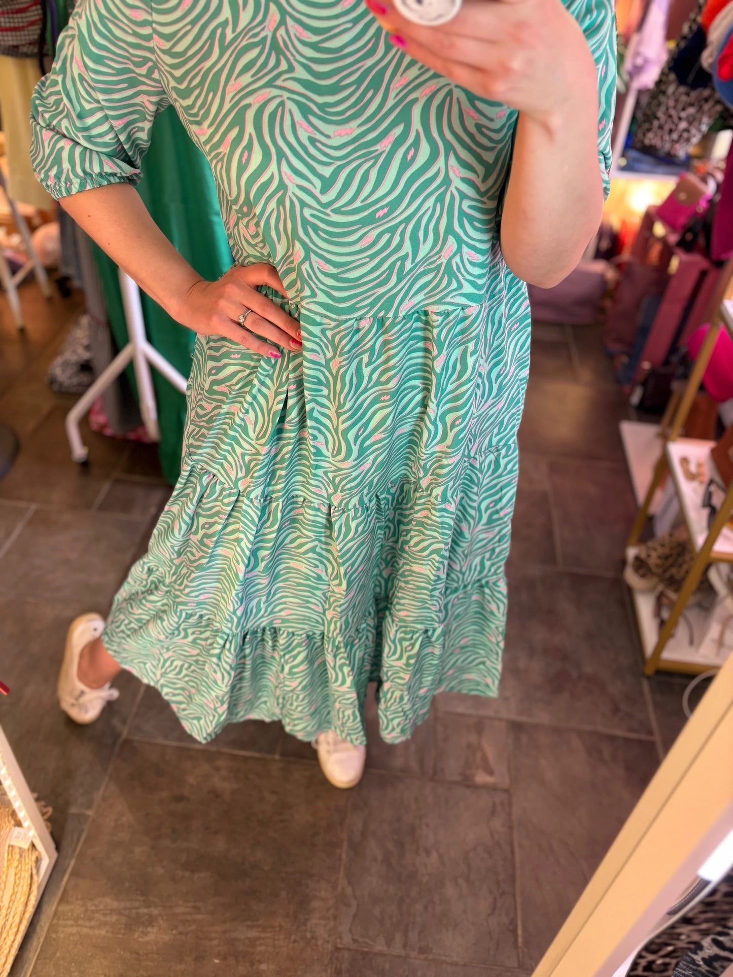 Person wearing a green patterned dress in a store setting