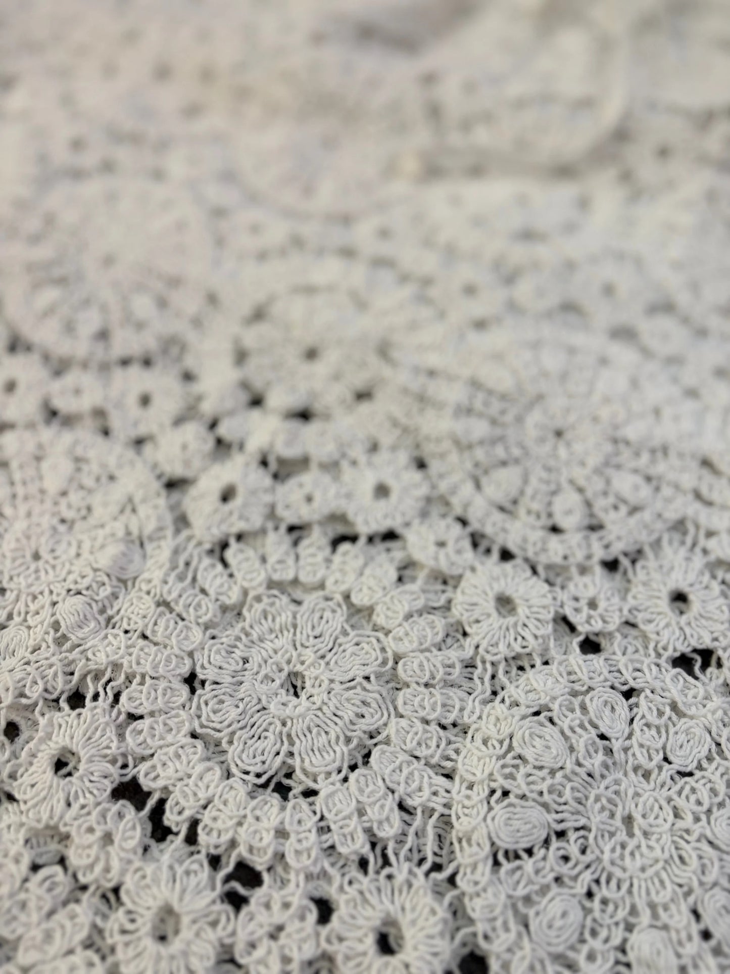 Close-up of intricate white lace fabric on a textured beige background