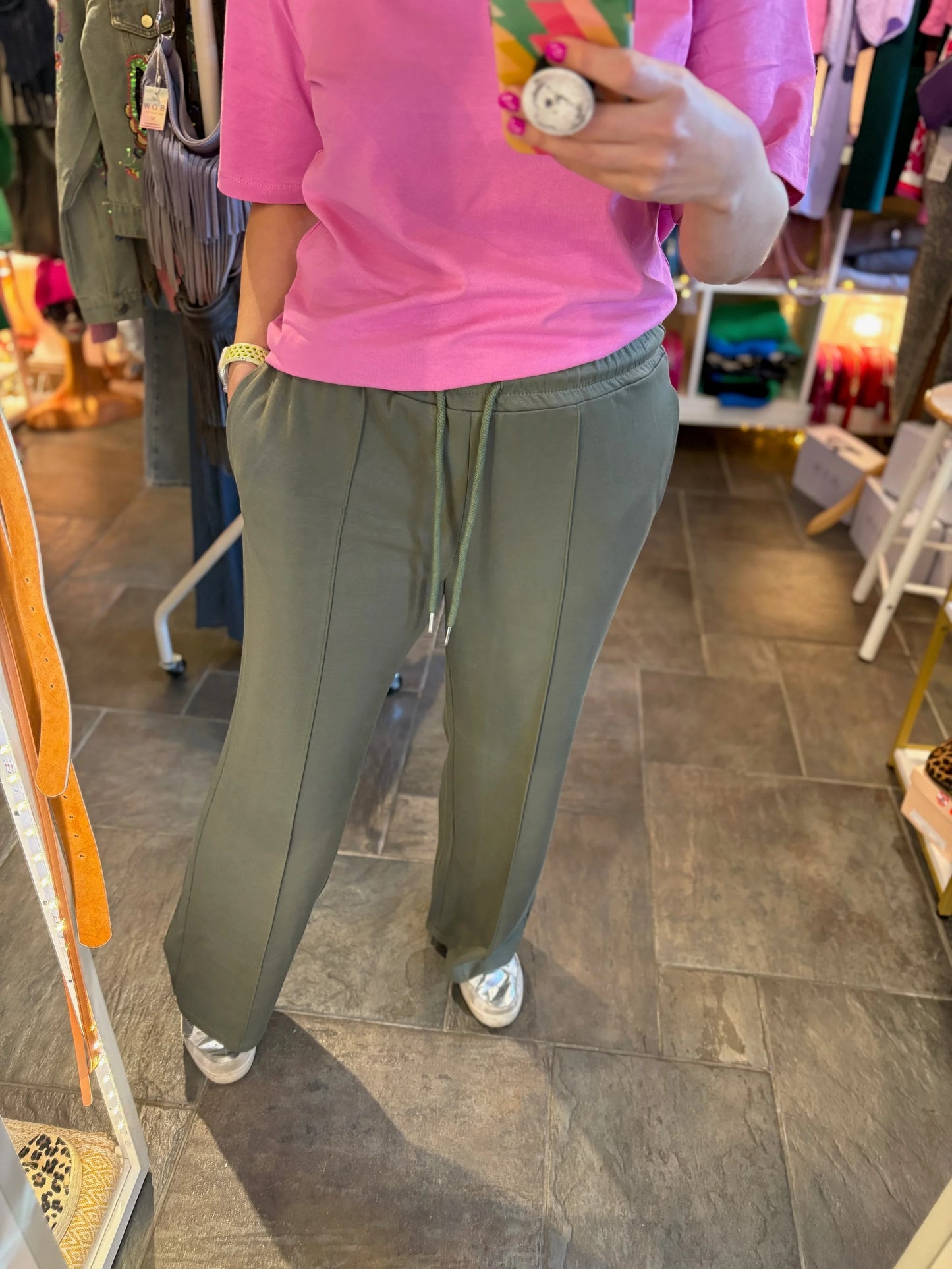 Person wearing a pink shirt and green pants in a store setting