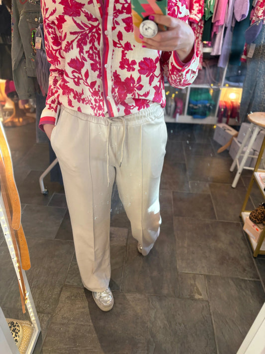 Person wearing a red floral jacket and white pants in a store setting