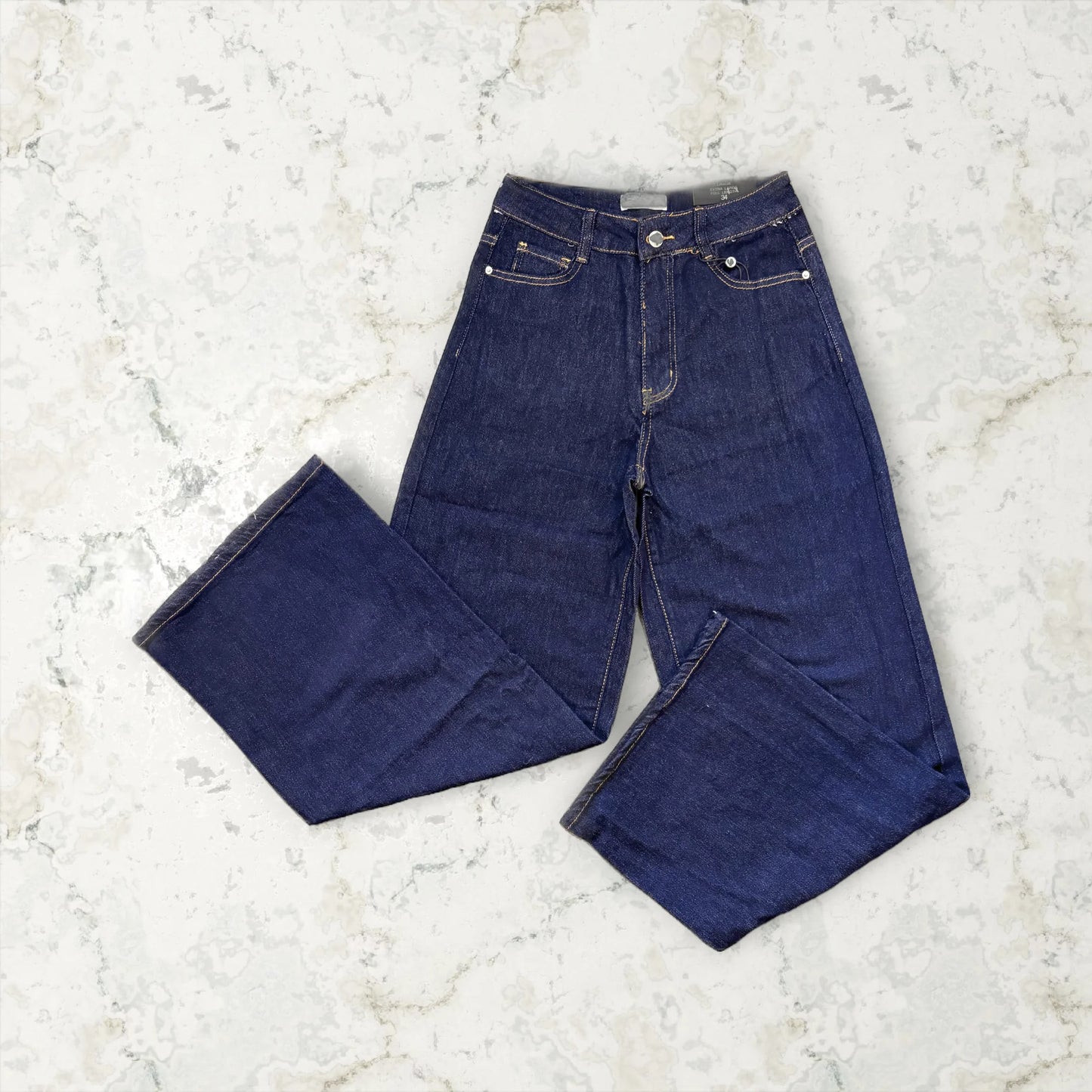 Pair of dark blue jeans on a light marble surface