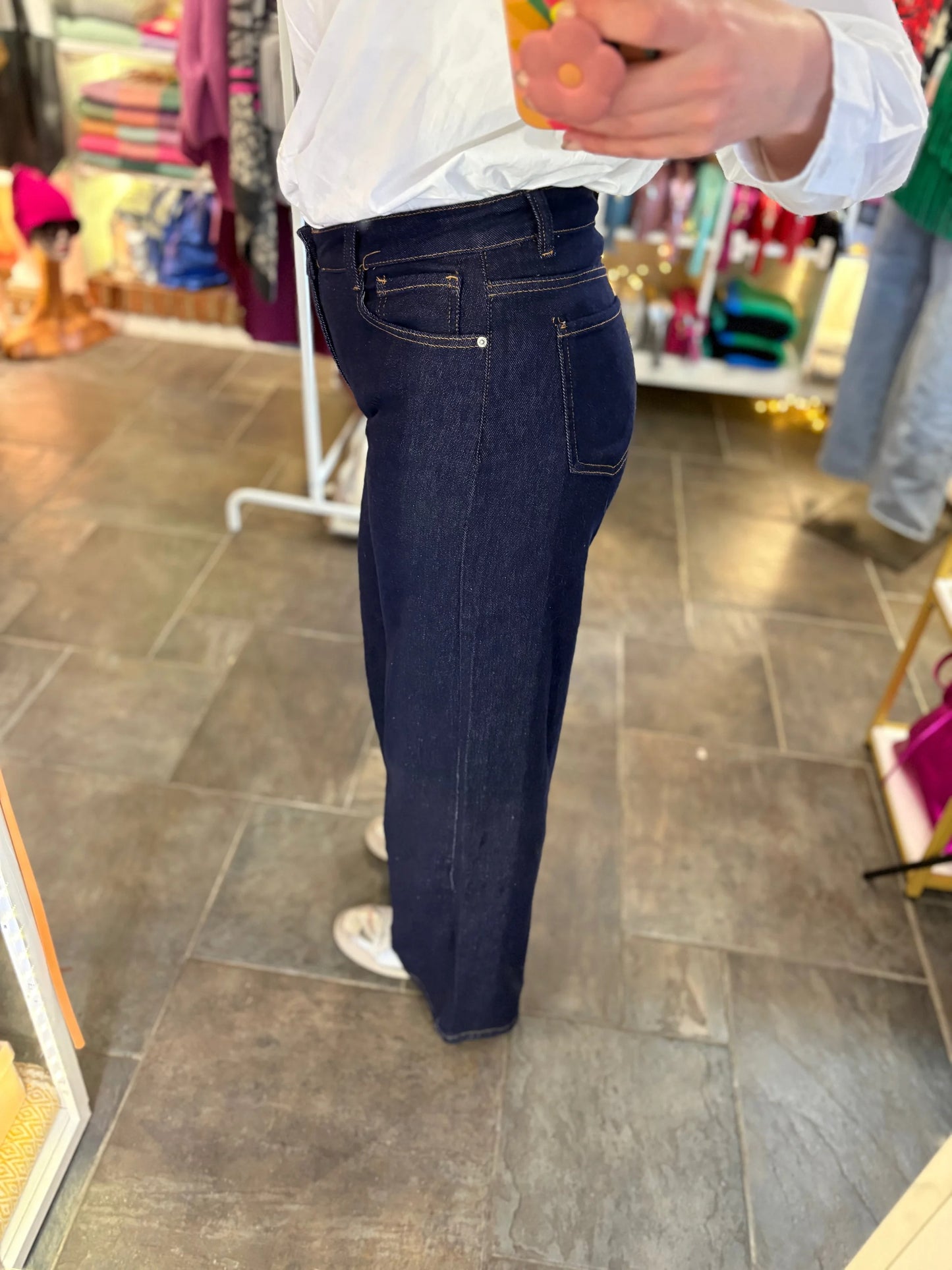 Person wearing dark blue jeans in a store setting