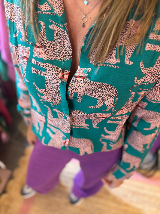 Person wearing a green and peach animal pattern blouse and magenta trousers