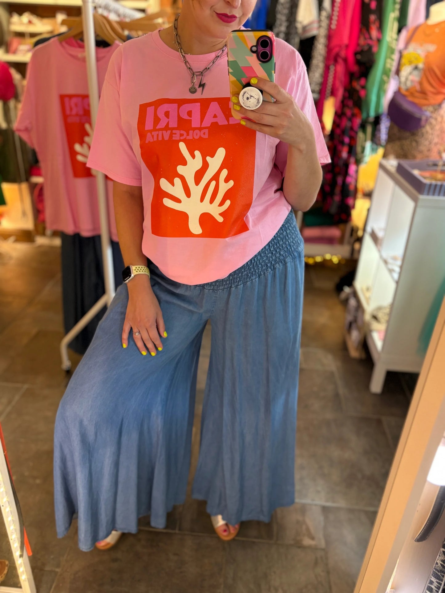 Person wearing a pink t-shirt with a red and white graphic design in a store setting.