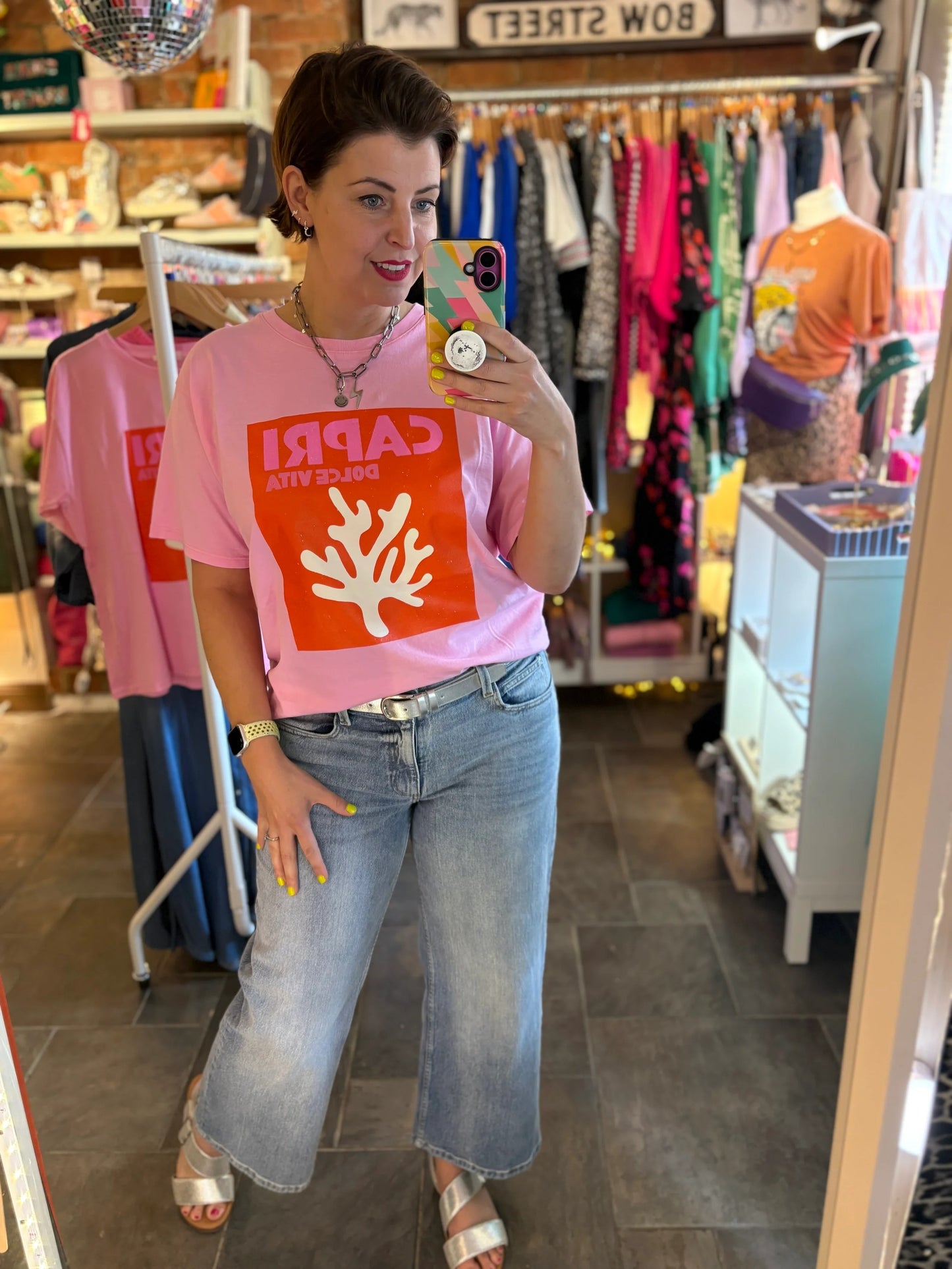 Person wearing a pink t-shirt with a coral design in a store setting