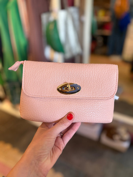 pale Pink leather look handbag held by a person with a blurred indoor background