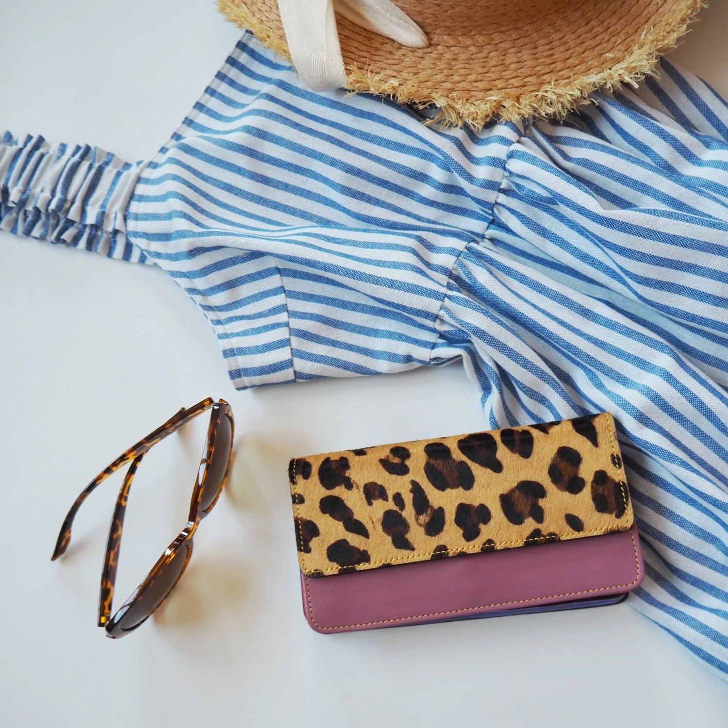 flat lay of summer products sunglasses, hat, dress, purse
