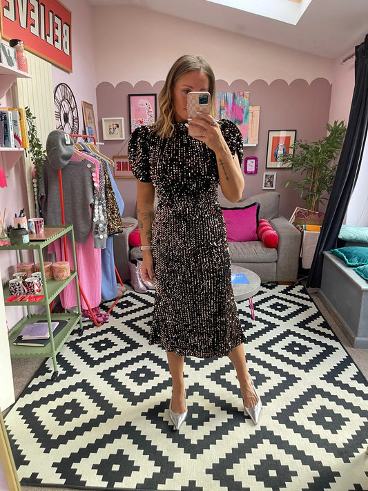 Woman taking a mirror selfie in a room with a patterned rug, colorful pillows, and decor.