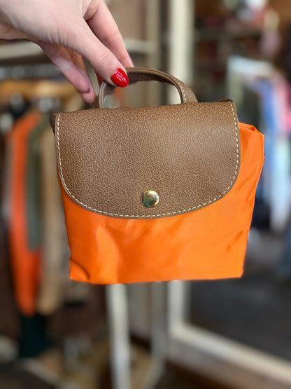 Hand holding a brown and orange bag with blurred background