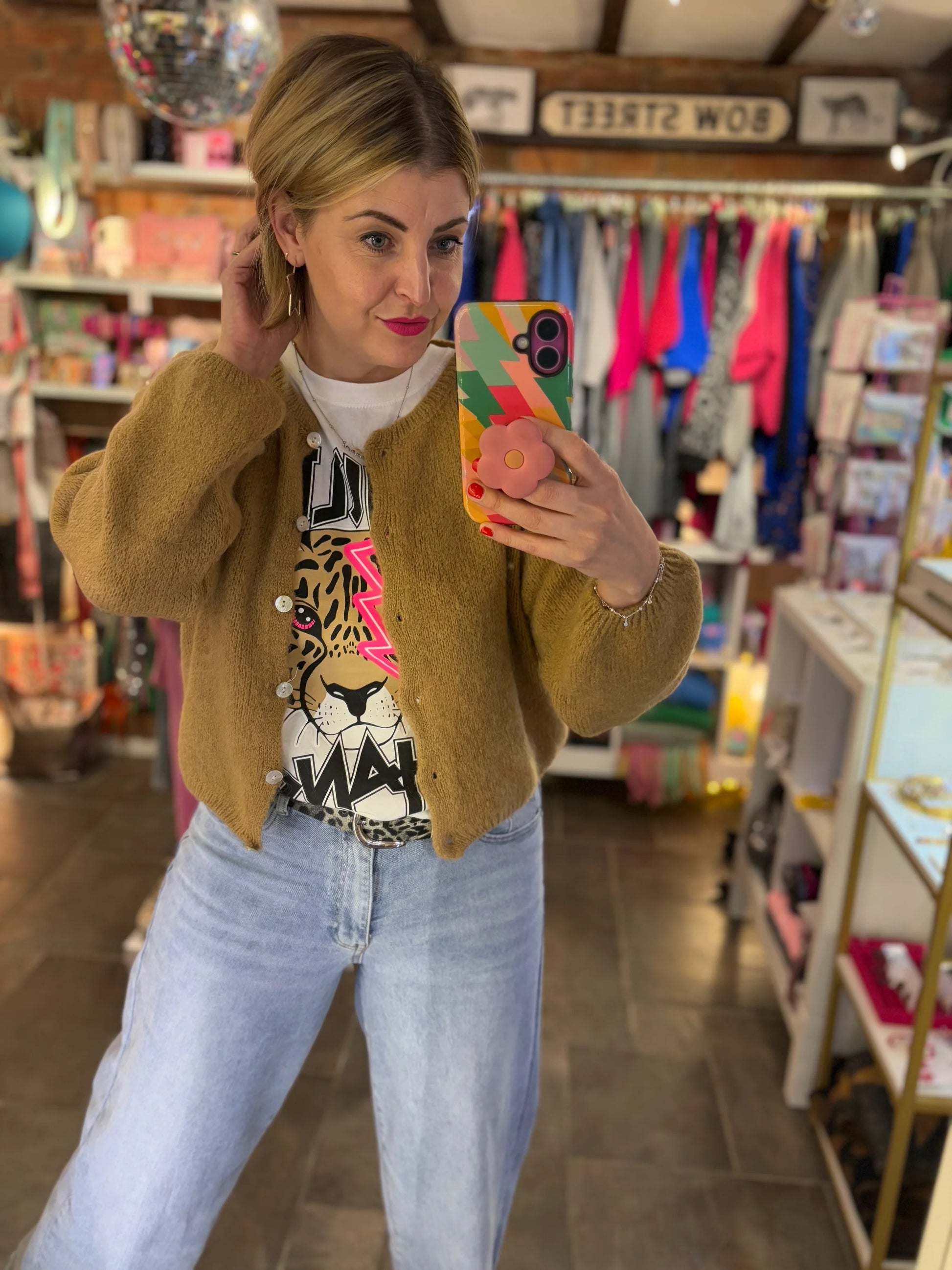 Woman taking a mirror selfie in a store with colorful phone case