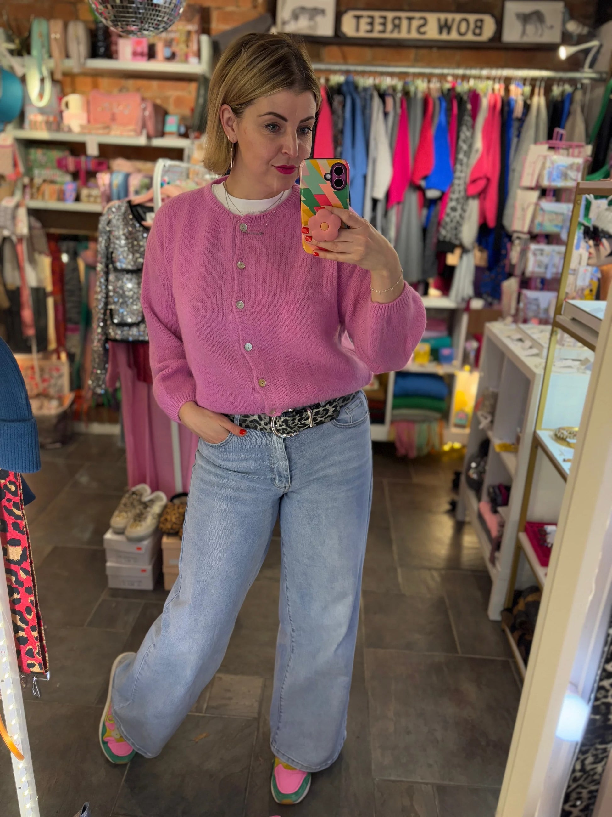 Person wearing a pink cardigan and blue jeans in a store setting