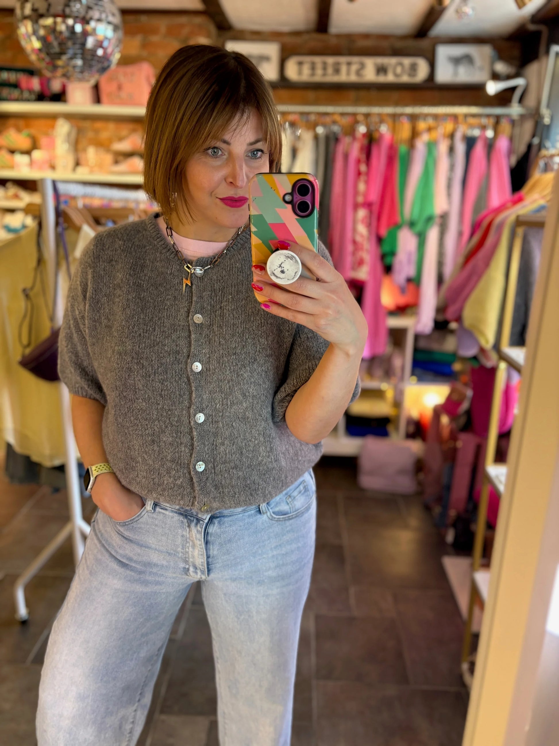 Woman taking a mirror selfie in a clothing store