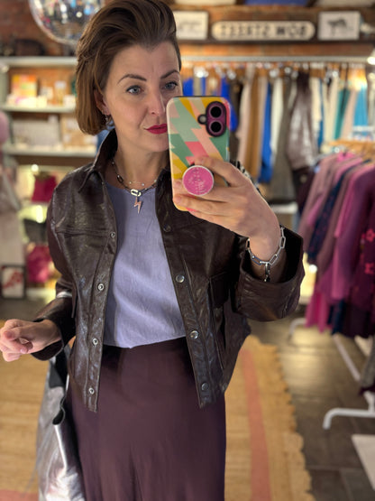 Woman Wearing a Dark Brown Short Leather Jacket, Lilac Top and Burgundy Slip Skirt