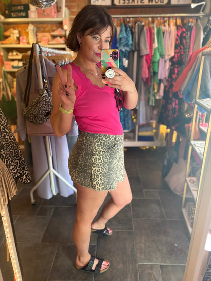 Woman taking a mirror selfie wearing a pink top and patterned skirt in a store.
