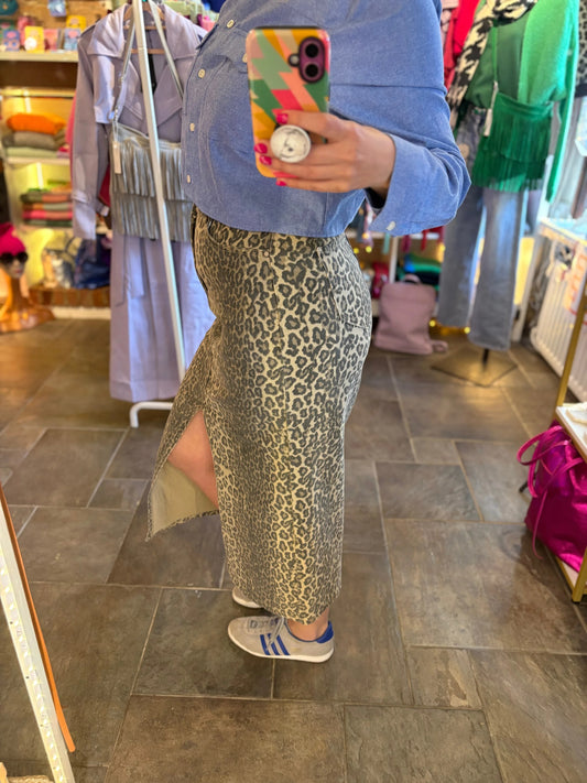 Person wearing a leopard print skirt and blue jacket in a store setting