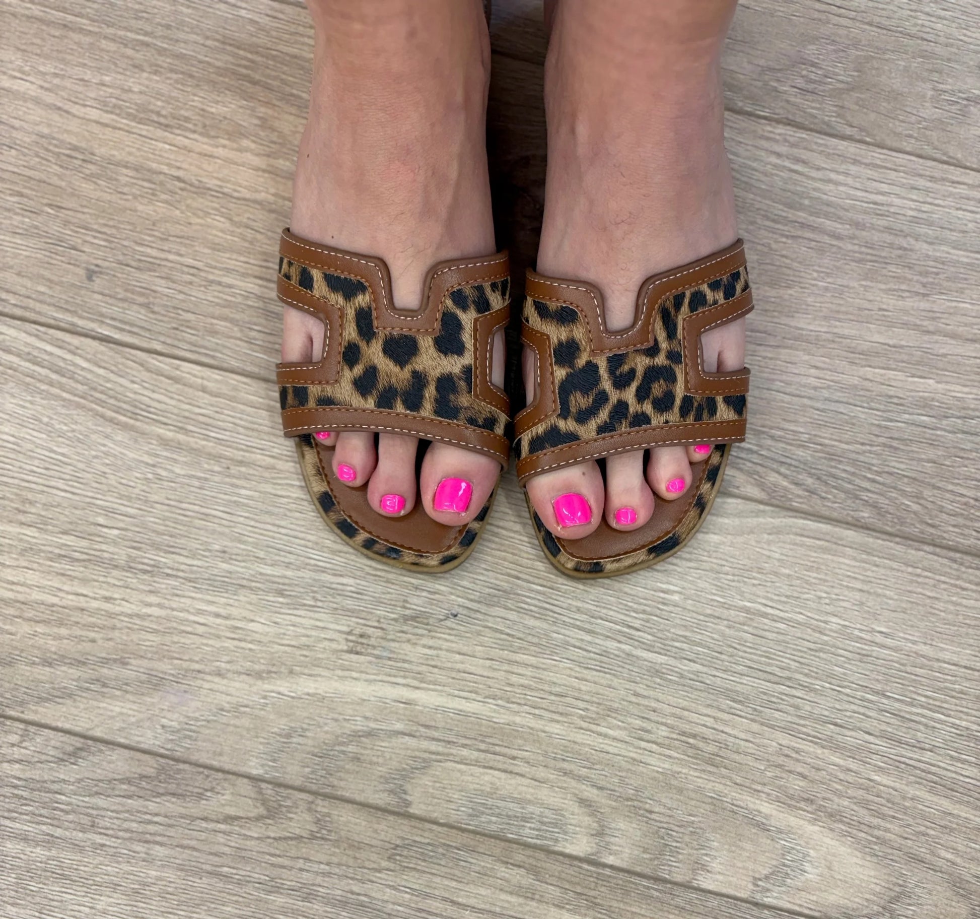 Leopard print sandals worn on a wooden floor
