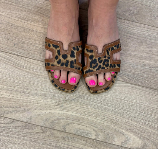 Leopard print sandals worn on a wooden floor