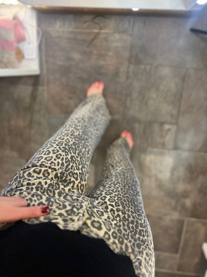 Person wearing leopard print pants standing on a tiled floor.