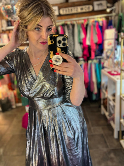 Woman taking a mirror selfie wearing a metallic dress in a store.