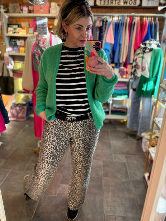 woman in shop taking selfie wearing green mohair cardigan and animal print jeans.