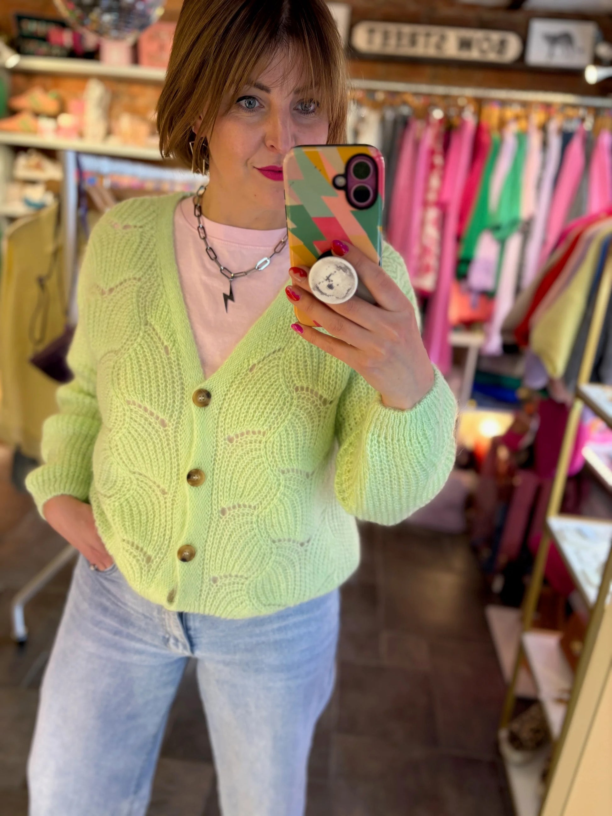 Person wearing a bright green cardigan in a clothing store.