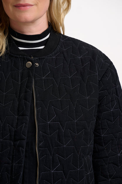 Close-up of a person wearing a black quilted jacket with geometric star pattern 