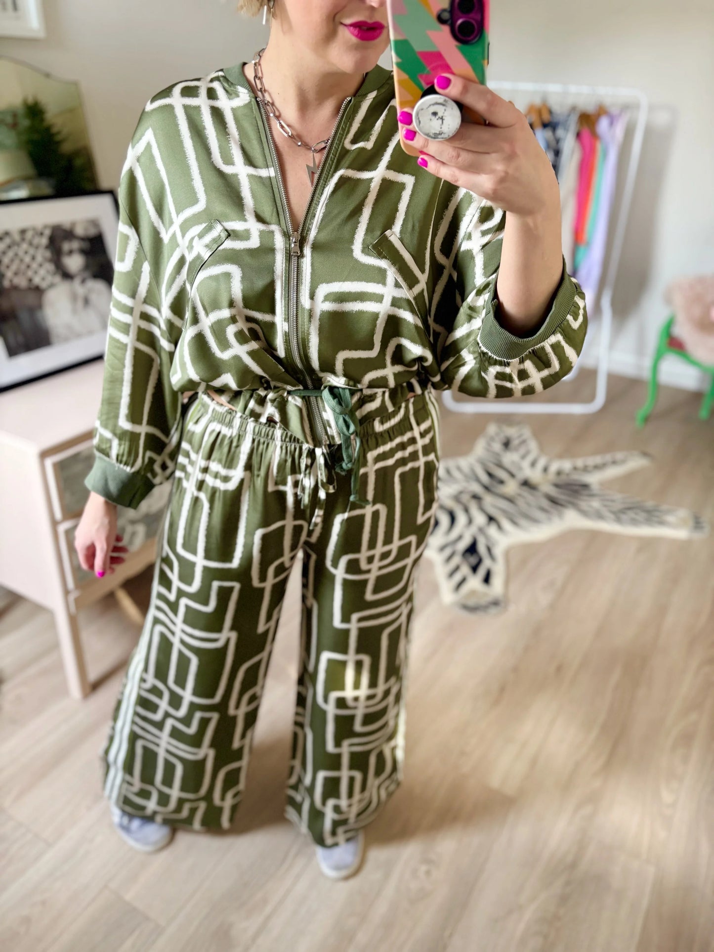 Person wearing a green patterned outfit taking a mirror selfie.