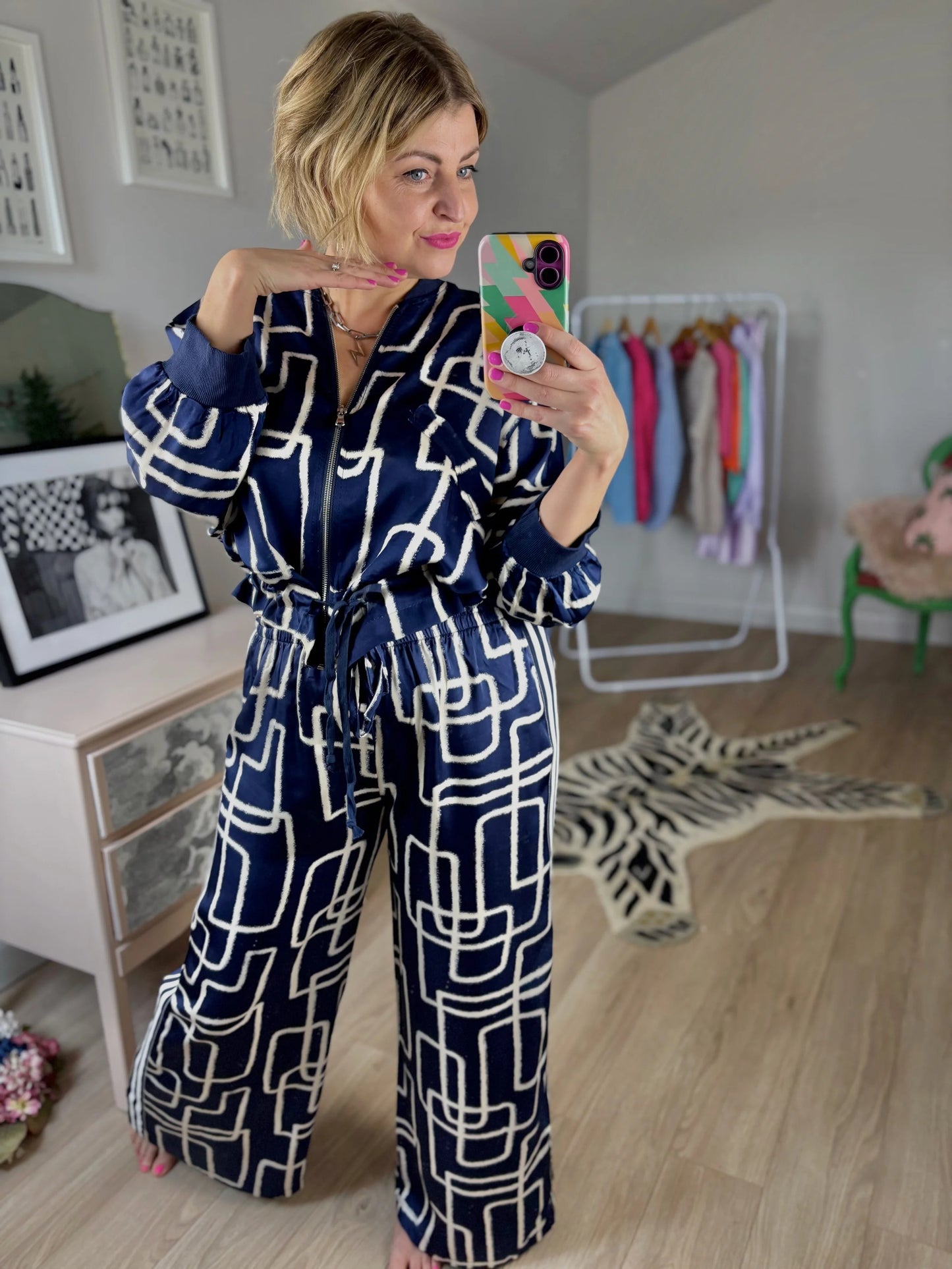 Person wearing a blue geometric patterned outfit taking a mirror selfie in a room.