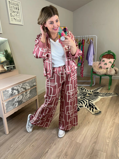 Woman taking a mirror selfie wearing a patterned outfit in a room with furniture and decor.