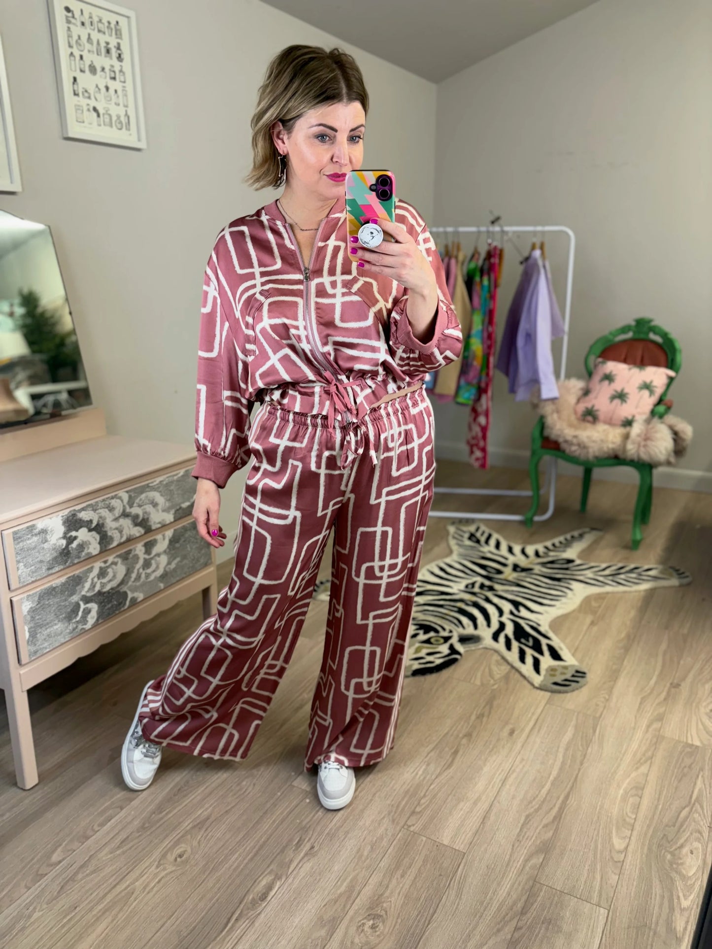 Woman taking a mirror selfie wearing a patterned outfit in a room with furniture and decor.