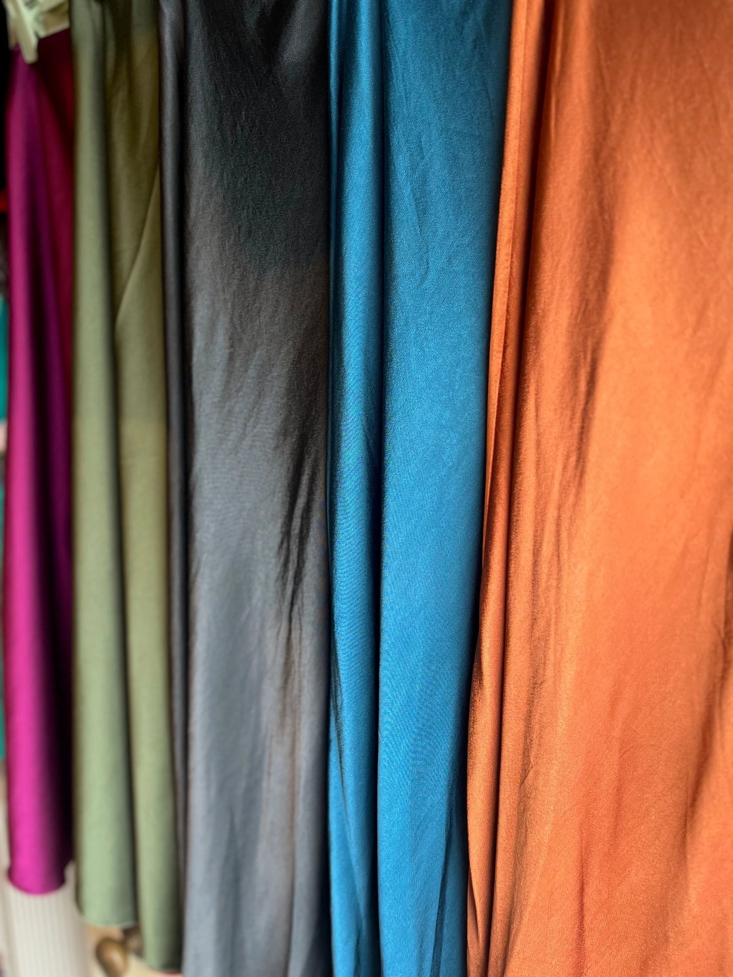 Close-up of various colored fabrics hanging on a rack.