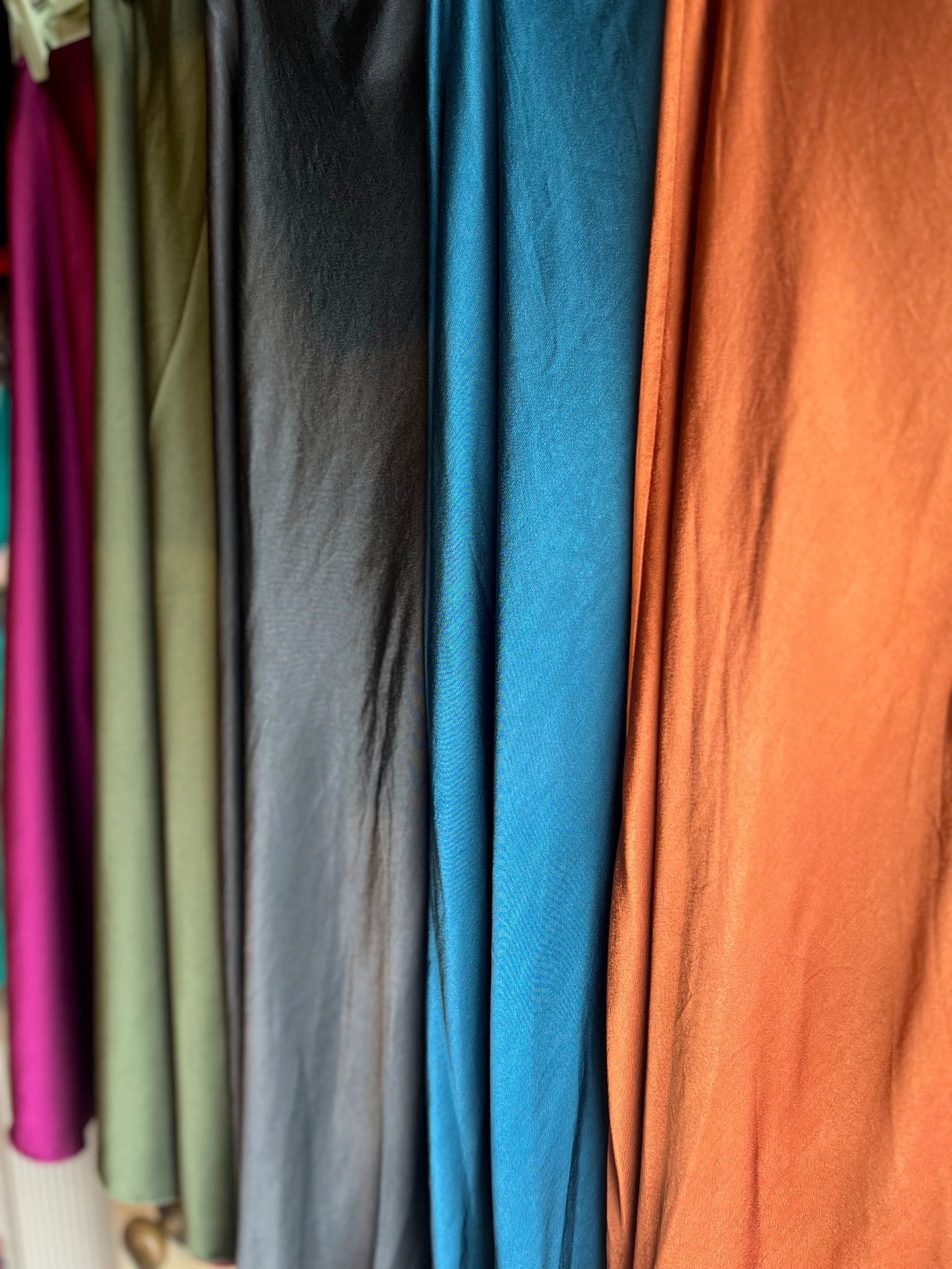 Close-up of various colored fabrics hanging on a rack.