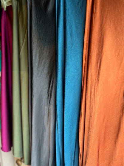 Close-up of various colored fabrics hanging on a rack.
