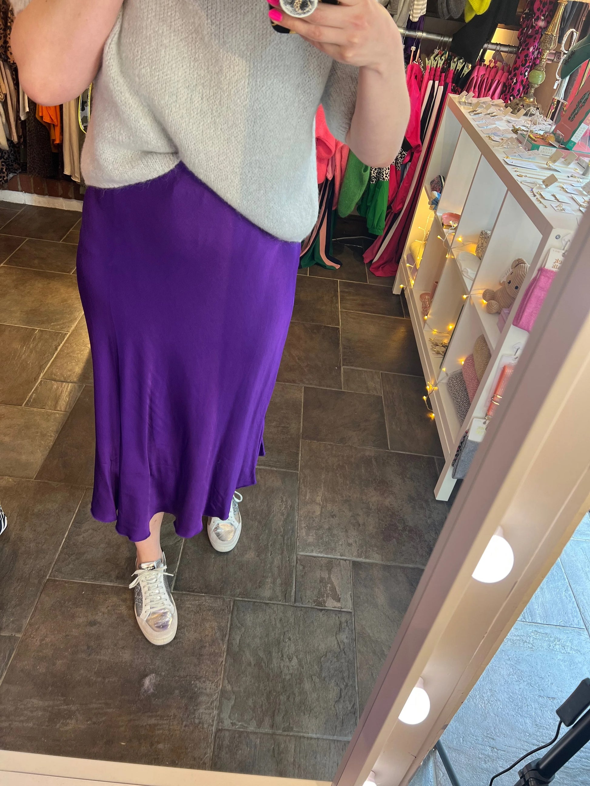 Person wearing a purple skirt and gray top in a store setting.