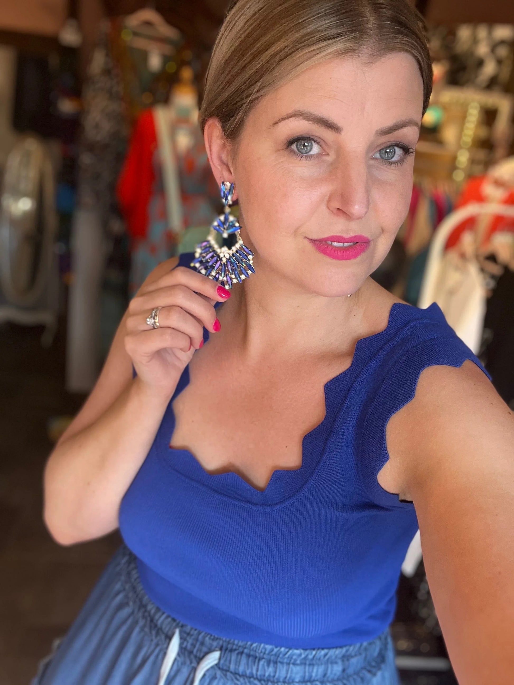 Woman wearing a blue top and large earrings in an indoor setting