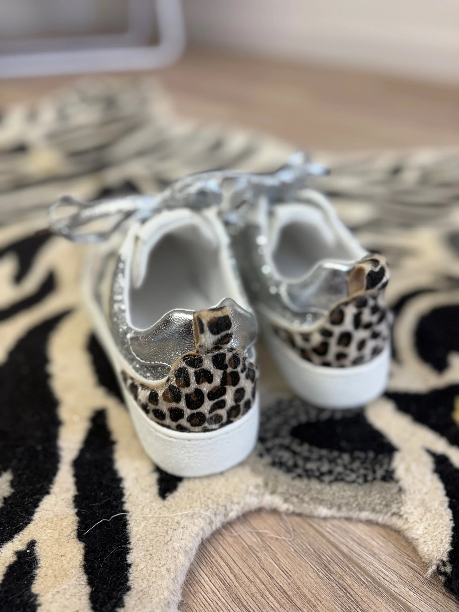 White sneakers with leopard print accents on a patterned rug