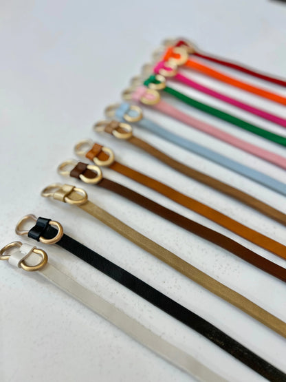 Set of colorful leather straps with gold buckles on a light background